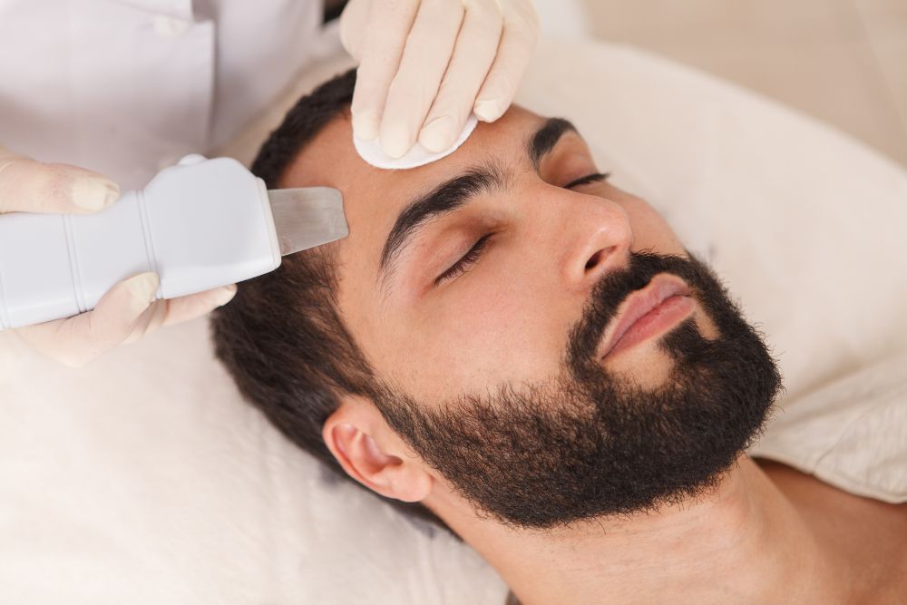 Hombre recibiendo tratamiento facial de limpieza en clínica estética
