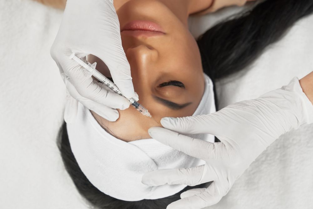 Dermatóloga aplicando baby botox en la frente de una paciente