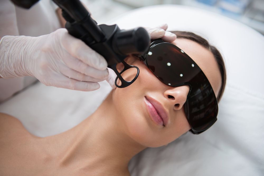 Paciente en camilla con gafas protectoras listas para procedimiento dermatológico de láser CO2